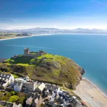 Golygfa o'r awyr o Gastell Cricieth ar y bryn, y dref yn y tu blaen a'r môr a bryniau pell yn y cefndir