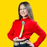 Merch ifanc mewn het draddodiadol Gymreig a siwmper goch yn dangos cenhinen wedi ei binio ar ei siwmper