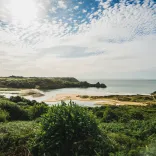 Golygfeydd dros Fae y Tri Chlogwyn o’r bryniau gwyrdd, tua’r môr a’r ffurfiannau tywod trawiadol.