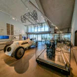 Tu fewn i Amgueddfa Cyflymder ym Mhentywyn, gyda char rasio hanesyddol Babs ac arddangosfeydd injans mewn oriel olau a modern.