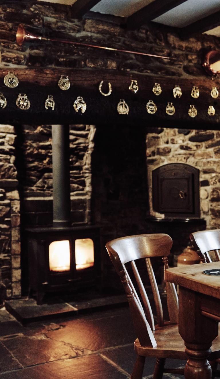 Table infront of a log fire built into a stone wall. Y Talbot, Tregaron, Mid Wales