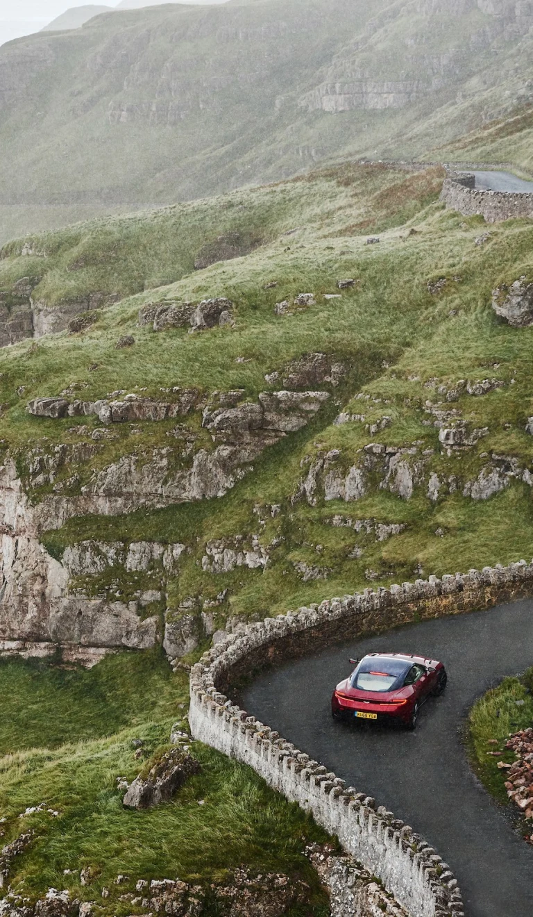 Car yn gyrru ar hyd ffordd droellog gyda'r môr ar yr ochr chwith