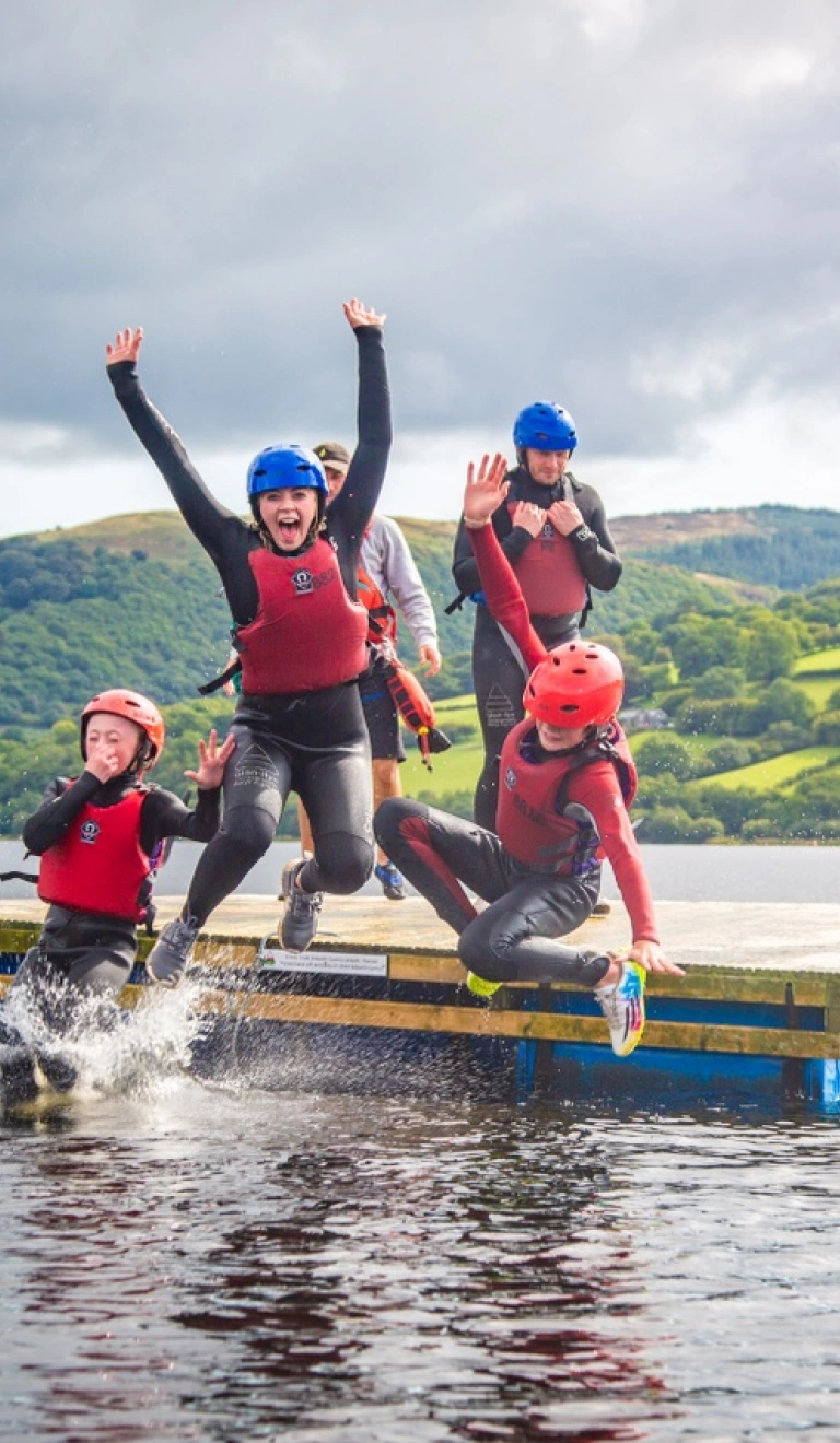 Criw yn neidio oddi ar rafft i fewn i Lyn Tegid. 