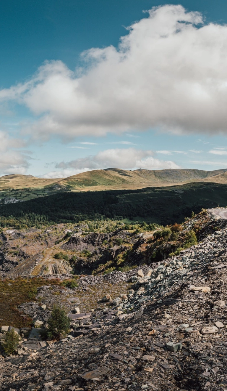 Quarry Kart yn Zip World yn erbyn cefndir o fynyddoedd a phwll glas.